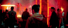 a man in a hoodie stands in a crowded room