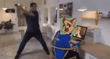 a man and a cat are fighting in a living room while a cat sits in front of a computer .
