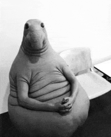 a black and white photo of a large stuffed animal sitting on a chair .