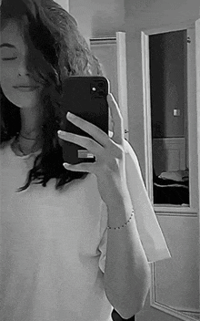 a woman is taking a selfie in a mirror with her phone .