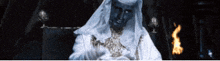 a man in a white robe is sitting in front of a flame