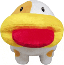 a yellow and white stuffed animal with a red tongue is sitting on a white surface .