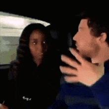 a man and a woman are sitting in the back seat of a car talking .