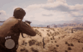a man is holding a gun in a desert with a cactus in the foreground