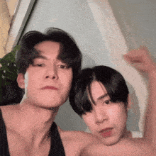 two young men are posing for a picture together and one of them is flexing his arm .