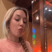 a woman wearing a braided ponytail and a pearl necklace is making a face .
