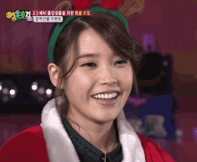 a woman wearing a headband with reindeer antlers and a santa suit smiles