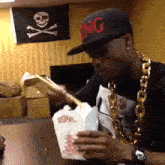 a man wearing a hat that says king is eating noodles
