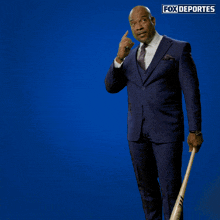 a man in a suit is swinging a baseball bat in front of a blue background that says " fox deportes "
