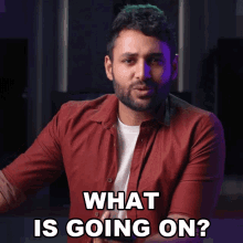 a man wearing a red shirt is asking what is going on