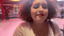a woman with curly hair and red lipstick is smiling in a pink room