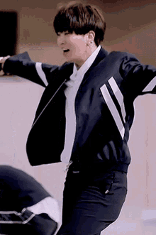 a young man in a black jacket and white shirt is dancing