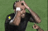 a man with a tattoo on his arm is holding his head while laughing .