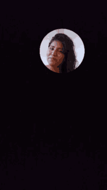 a woman 's face is shown in a circle on a dark background