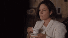 a woman in a white jacket is sitting in a dark room