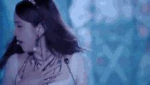 a woman is standing in front of a blue background and holding her chest .