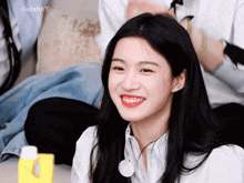 a girl with long black hair is smiling in front of a gulubby watermark