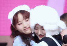 a girl wearing a sheep hat hugs another girl