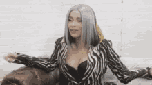 a woman with gray hair is sitting on a couch wearing a zebra print jacket and bra .