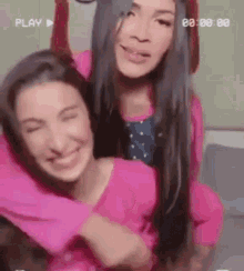 two women are hugging each other and smiling in a video tape .