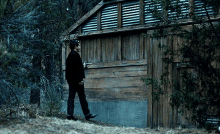 a man standing in front of a wooden building with a gun in his hand