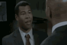 a man in a suit and tie is laughing with another man in a suit .