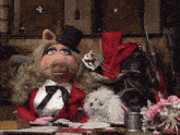 miss piggy sits at a desk with a dog