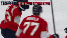a hockey player wearing a number 77 jersey stands on the ice