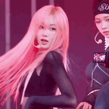 a girl with long pink hair is dancing on stage