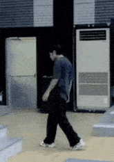 a man is walking on a wooden floor in a room next to a large air conditioner .