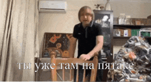 a man in a black shirt is standing in front of a chair with the words " ты уже там на пятаке " on the bottom