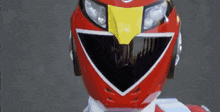 a close up of a red power ranger helmet with a yellow eagle on it .
