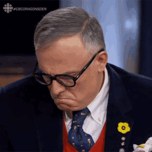 a man wearing glasses and a tie with a yellow flower pin