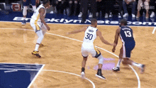 a basketball player with the number 30 on his jersey is dribbling the ball