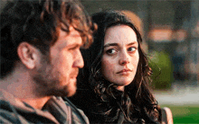a man and a woman are sitting next to each other and the woman is looking at the man