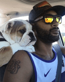 a man with a tattoo on his arm is holding a small dog
