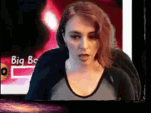 a woman is sitting in front of a screen that says big bc