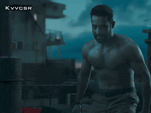 a shirtless man is standing in front of a building with the letters kvvcsr visible