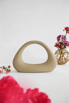 a vase with pink flowers sits next to a ceramic sculpture
