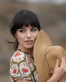 a woman covering her face with a hat and a necklace