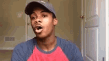 a man wearing a hat and a blue shirt is making a funny face .
