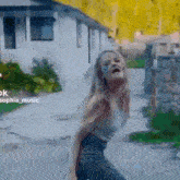 a woman is standing on a sidewalk in front of a house .