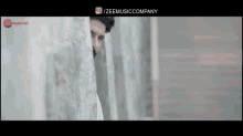 a man peeking out from behind a wall with the words / zeemusiccompany below him