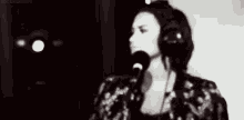 a woman wearing headphones is singing into a microphone .