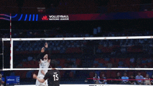 a volleyball player wearing number 15 jumps to block another player