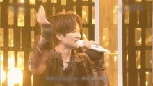 a man singing into a microphone with his hand up