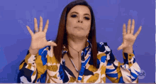 a woman in a colorful shirt is making a funny face with her hands up
