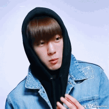 a young man wearing a black hoodie and a denim jacket that says sdl on it