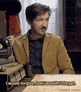 a man sitting at a table with the words i would forgive but i would n't forget