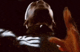 a close up of a person 's face with their hands up in the air in a dark room .